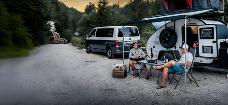 Campters sitting outside a RV  enjoying the outdoors.