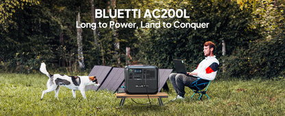 BLUETTI AC200L portable power station in a grassy area, connected to a laptop, with solar panels in the background.