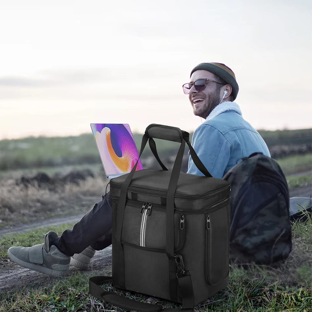 Man using laptop outdoors next to portable generator bag on grass, renewable energy solution