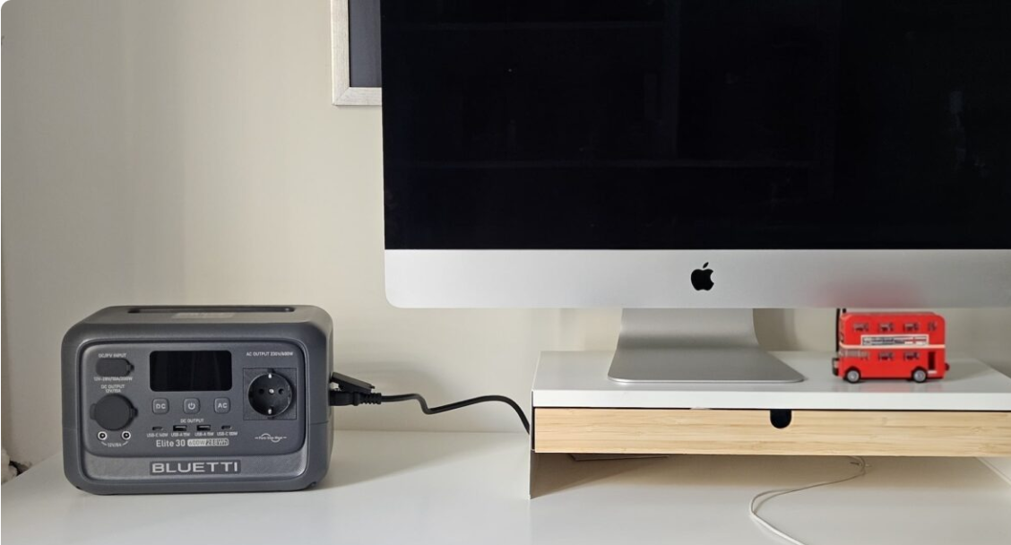 Portable Bluetooth speaker connected to a computer monitor on a desk.