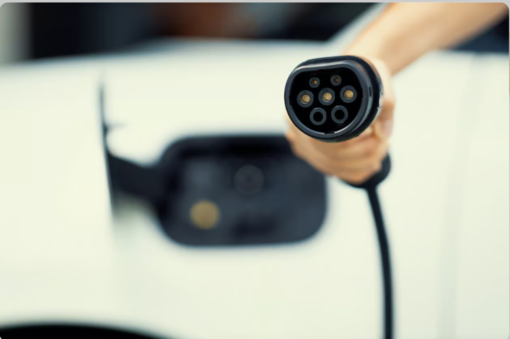 Hand holding an electric vehicle charging cable connector with a blurred background